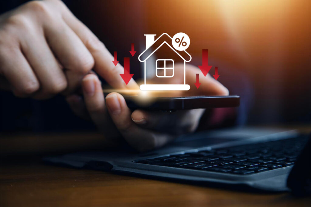Businessman use smartphone with virtual home icon and down arrow for economical real estate and lower mortgage interest rates. Reduced prices for rental housing, Demand for home purchases decreases.