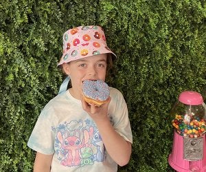 June Holidays for Kids: A Kid-Friendly Celebration for Every Day Kid eating a donut wearing a donut hat - Photo by Kelly Patino for Mommy Poppins National Donut Day